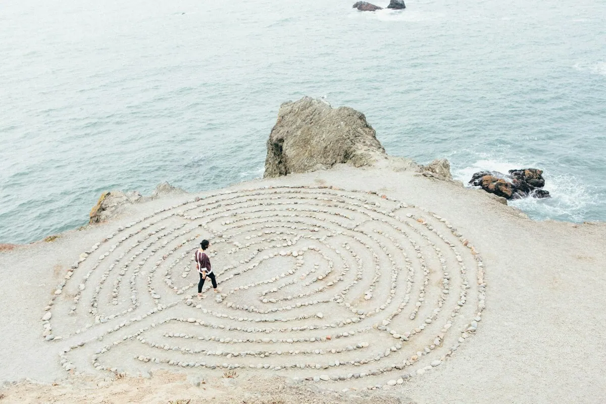 Person walking through a labyrinth by the ocean, symbolizing overcoming confusion and stuckness