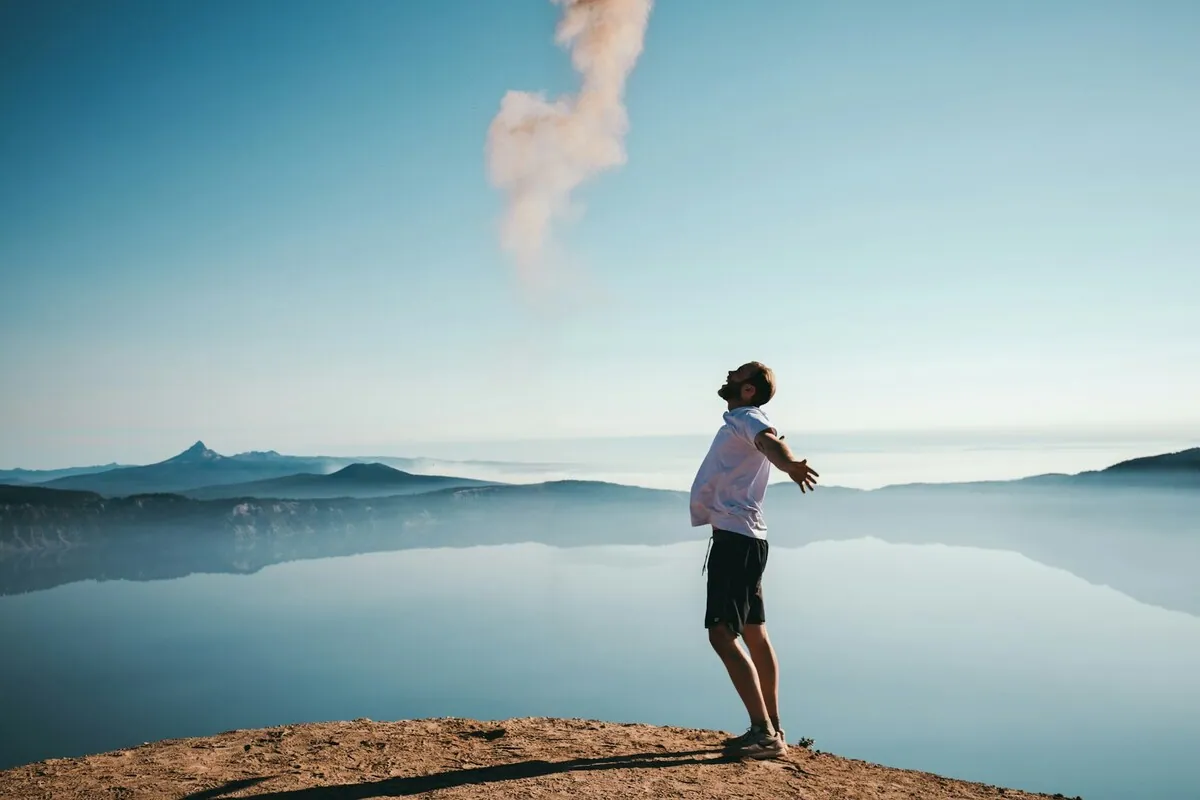 Person standing on a mountain top, feeling free and overcoming negative feelings