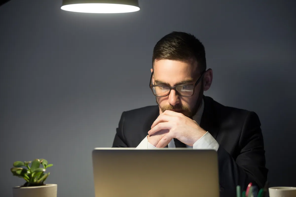 A businessman deep in thought, working late at his desk to overcome distraction problems.